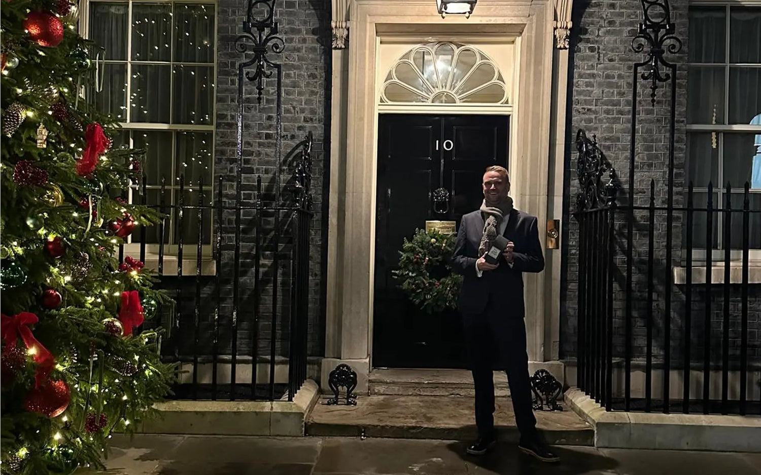 A team member of Project Harmless was invited to Downing Street and poses next to the Christmas tree outside Number 10 in December 2025.