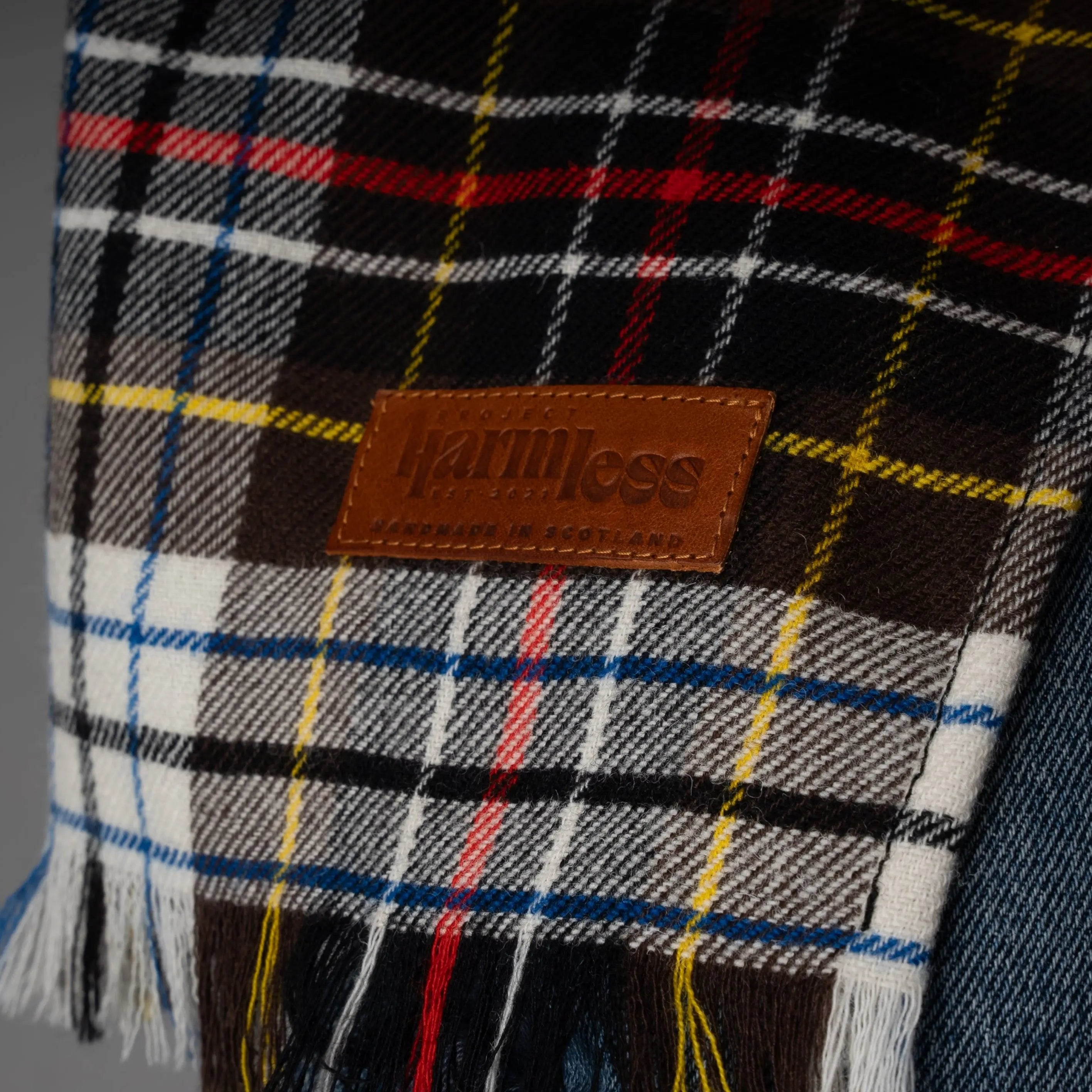 Close-up of the Project Harmless 1970 Commonwealth Games Collection scarf, showcasing the rare, revitalized tartan originally woven for Scotland’s first-ever Commonwealth Games. This limited-edition, sustainable scarf is handcrafted in Scotland, highlighting premium heritage fabric and timeless craftsmanship. A symbol of eco-conscious luxury and Scottish textile artistry.