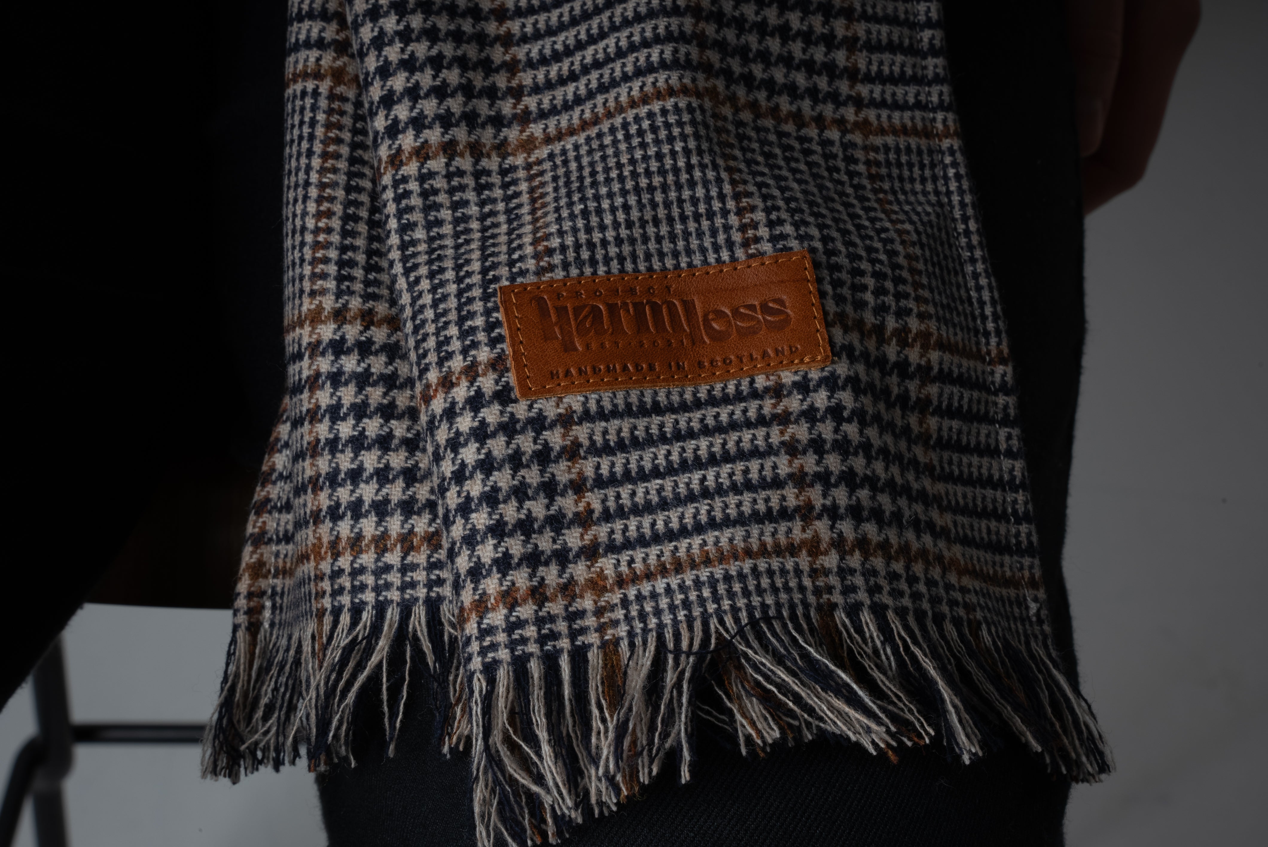 Close-up view of the Harmless Atelier District Check Merino Wool Scarf by Project Harmless, showcasing its luxurious texture and finely woven pattern. Crafted in England from 100% pure Merino wool, this Scottish-designed sustainable scarf embodies timeless elegance and premium craftsmanship.