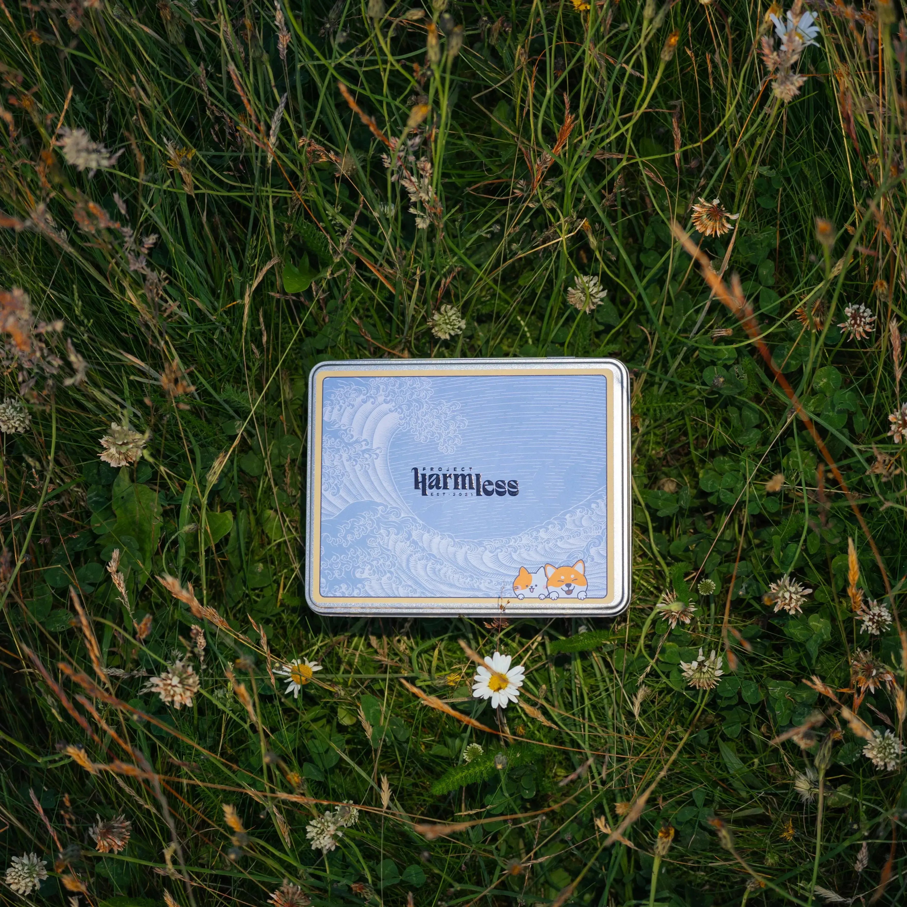 Project Harmless eco-friendly dog poop bag tin in grass with flowers — award-winning sustainable and cute pet waste solution
