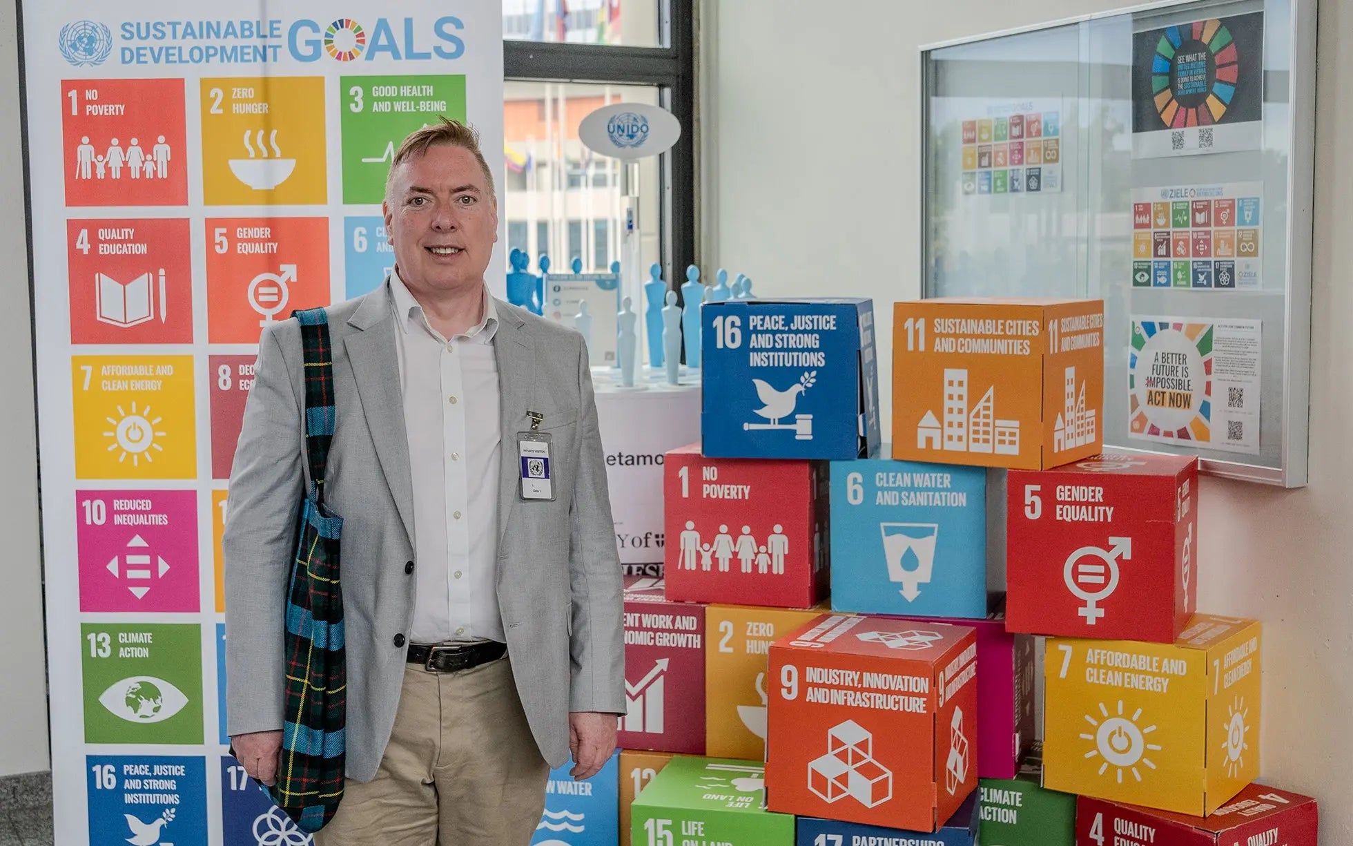 George Greer, Co-Founder of Project Harmless, standing next to a poster of the United Nations' Sustainable Development Goals United Nations Office at Vienna.