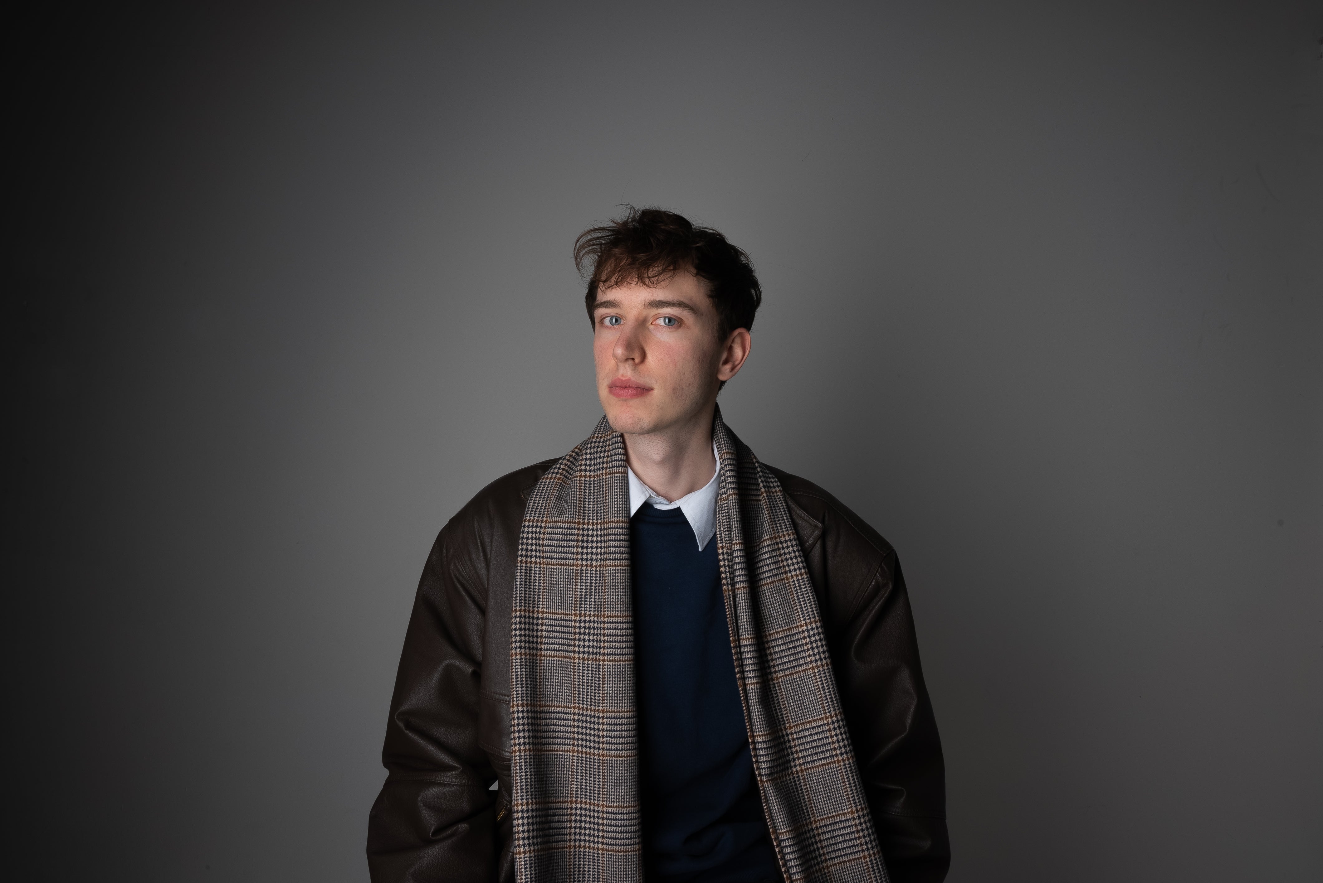 Male model wearing the Harmless Réservé Merino Wool Lake District Scarf, handcrafted in Scotland by Project Harmless, photographed in a studio.