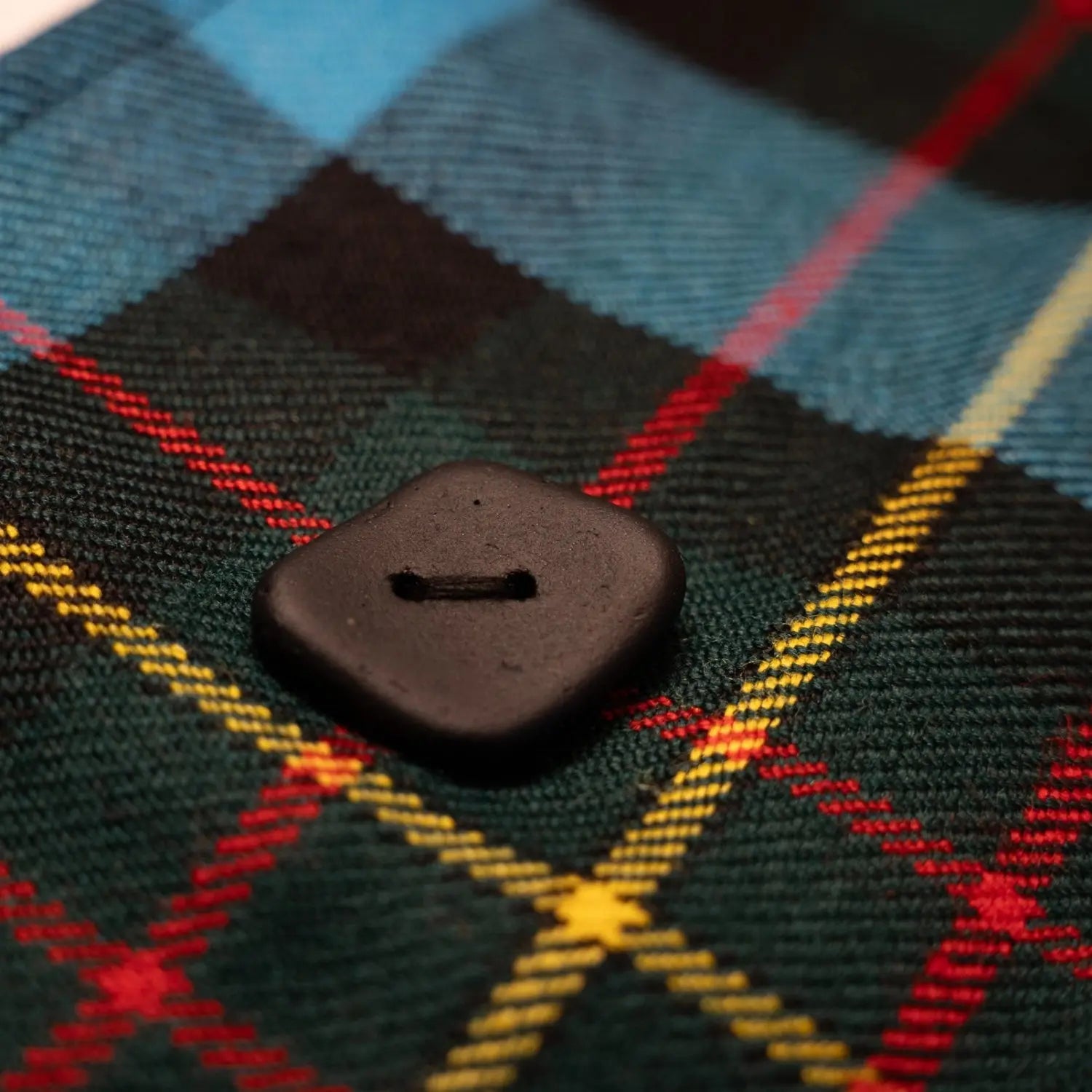 Close-up of the unique sea glass button on the Réservé MacLaren Scarf, a sustainable fashion piece handmade in Scotland. The upcycled button, crafted from reclaimed sea glass, adds an eco-luxury touch to this limited-edition accessory by Project Harmless.