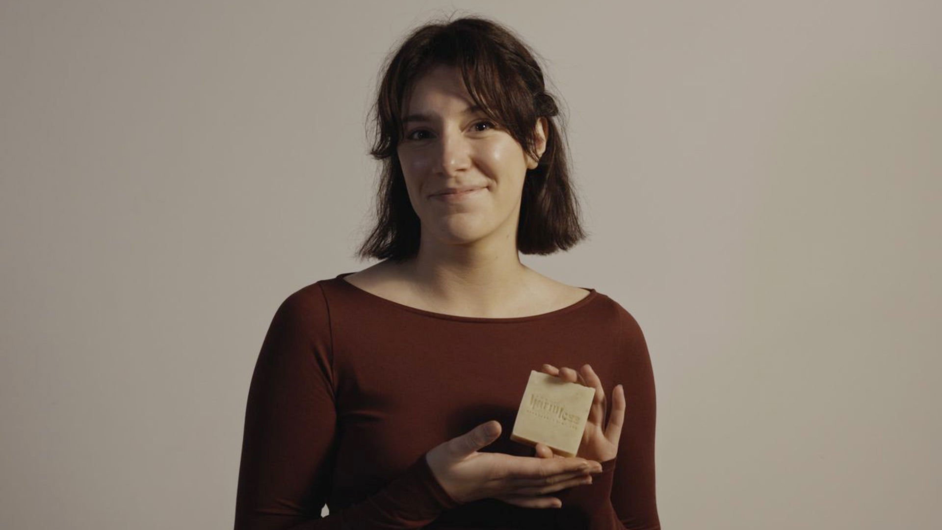 Harmless Apothecary model holding a Mugwort Rejuvenating Soap featuring a hand-stamped Project Harmless logo and ‘Handmade in Scotland’ text. Crafted using premium ingredients, this eco-friendly soap is 28-day cured for quality and sustainability. Perfect for those seeking natural, ethically made skincare products.