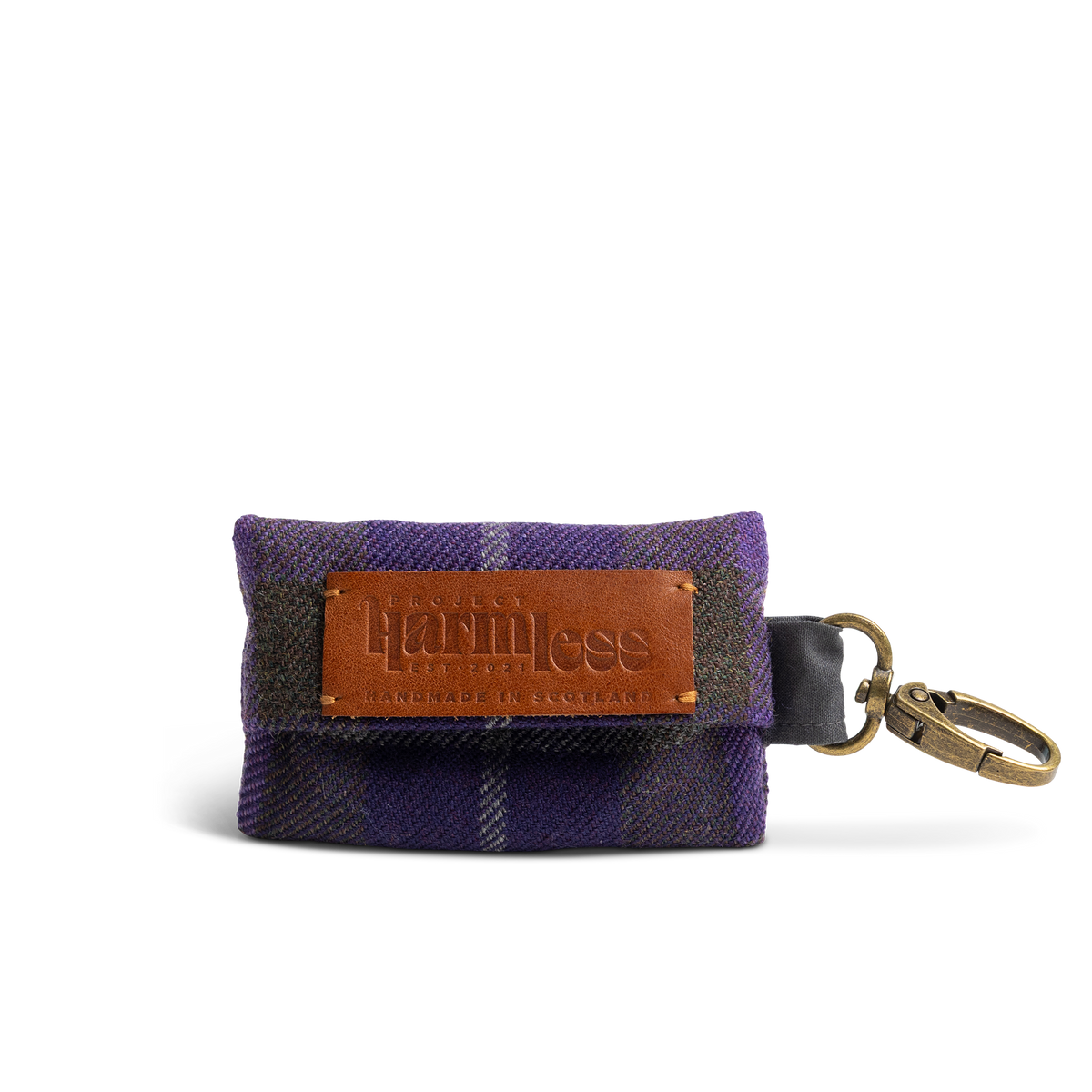A small tartan poo bag holder in purple tartan, with a brown leather brand patch reading 'Project Harmless' and 'Handmade in Scotland'