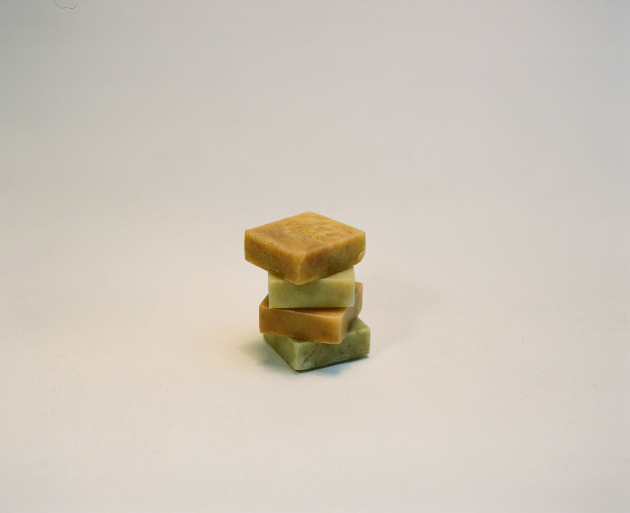 A stack of four handcrafted Project Harmless soaps, elegantly arranged against a white studio background. Each bar is enriched with organic essential oils, shea butter, and botanical extracts, handmade in Scotland and cured for 28 days. Palm oil-free, plastic-free, and designed for a luxurious cleansing ritual.